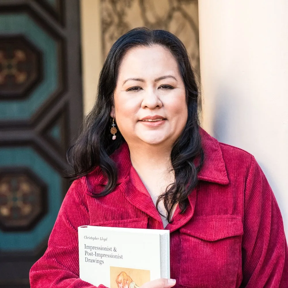 Frances wearing a red dress with Post Impressionist book and big smile